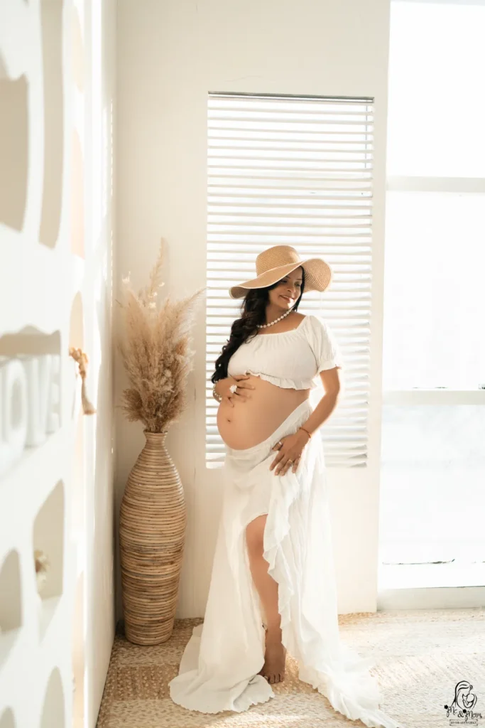 Expecting mother wearing a designer maternity gown during an indoor maternity photoshoot at Me & Mom Studio in Pune.