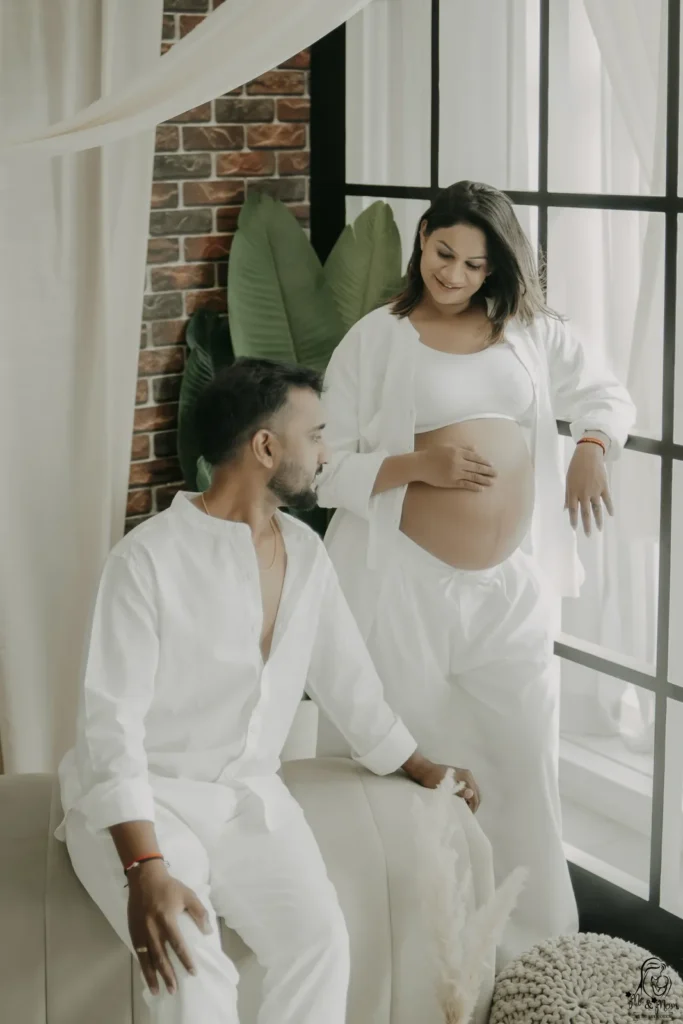 Pregnant couple posing during an indoor maternity photoshoot in Pune at Me & Mom by DB ARTWORKS.